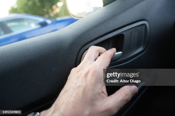 a man opens or closes a car door in a car park. - car door stock pictures, royalty-free photos & images