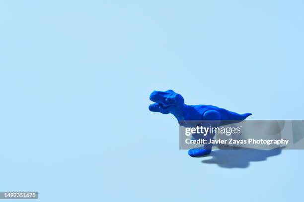 blue plastic tyrannosaurus rex on blue background - reptile stock pictures, royalty-free photos & images