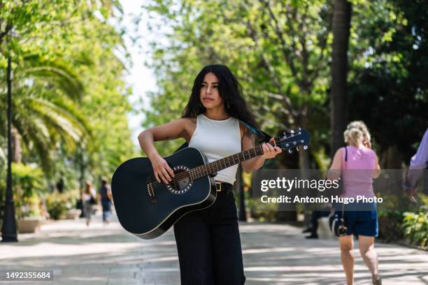 portrait of a south american girl playing her guitar in a park. - musician portrait stock pictures, royalty-free photos & images