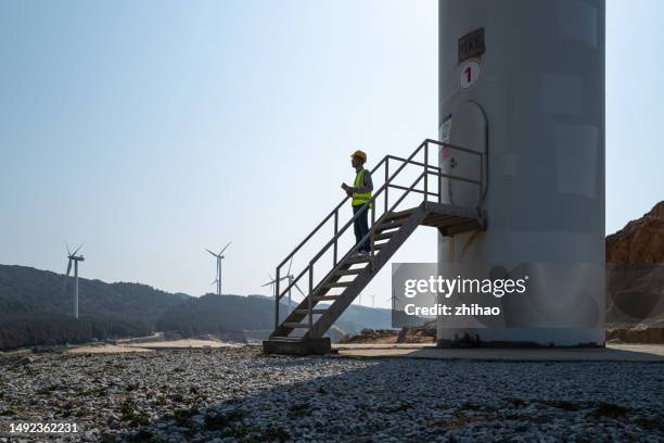 technicians work next to wind turbines - low carbon technology stockfoto's en -beelden