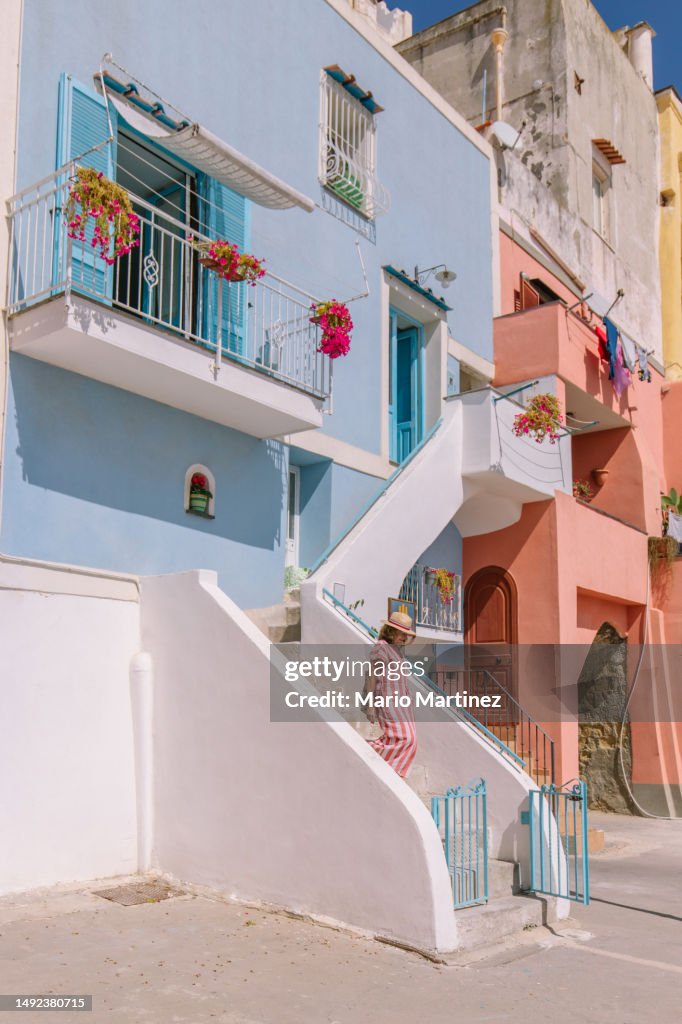 Woman walking downstairs of colorful building with balconies decorated with flowers