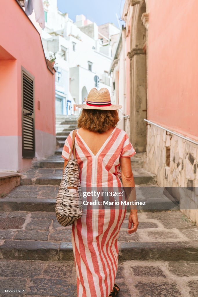 Unrecognizable woman walking on narrow and paved street