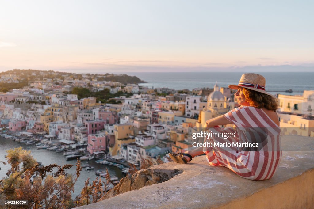 Mature woman admiring Procida sunset cityscape
