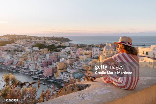 mature woman admiring procida sunset cityscape - mediterranean tour stock pictures, royalty-free photos & images