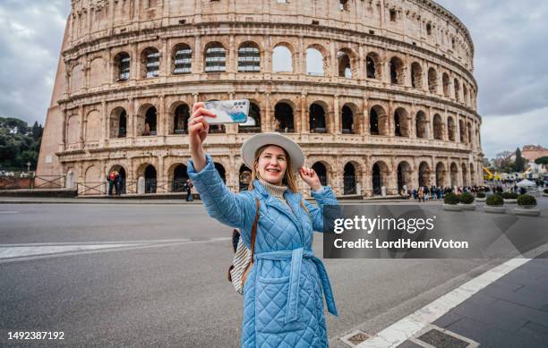 young woman taking selfie in front of the colosseum in rome - rome colosseum stock pictures, royalty-free photos & images