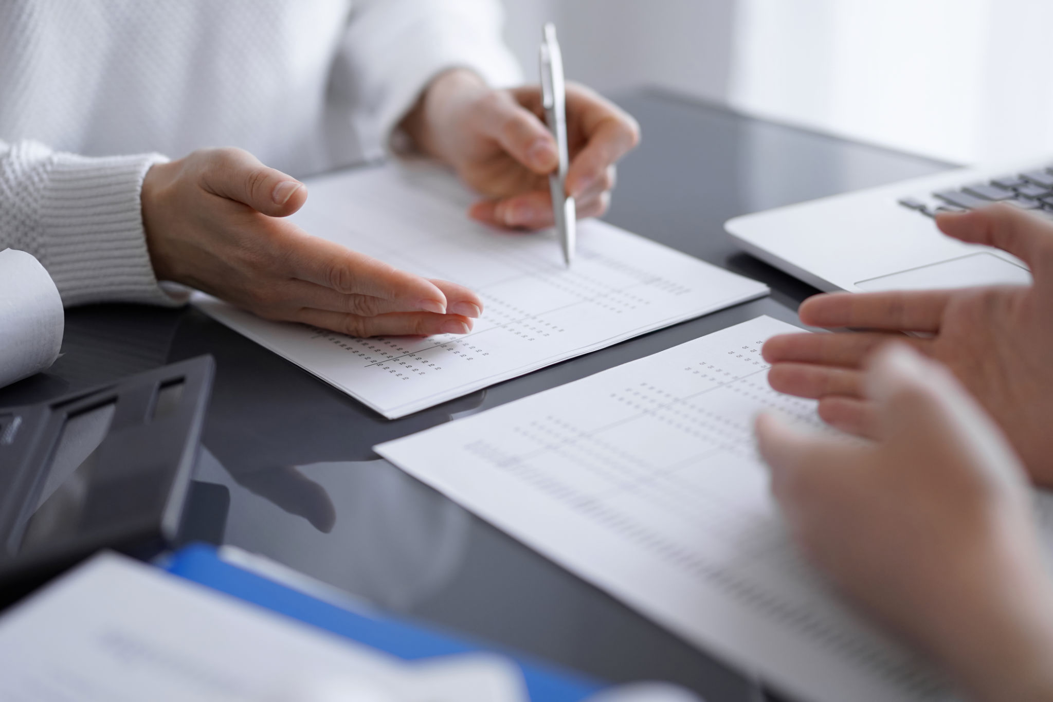 Woman accountant using a calculator and laptop computer while counting and discussing taxes with a client. Business audit concepts Woman accountant using a calculator and laptop computer while counting and discussing taxes with a client. Business audit concepts