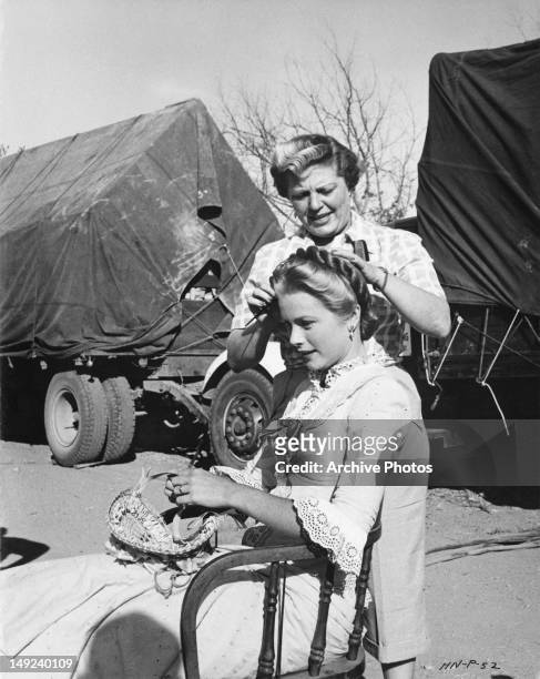 Hairdresser prepares American actress Grace Kelly for a scene in the western 'High Noon', circa 1951.