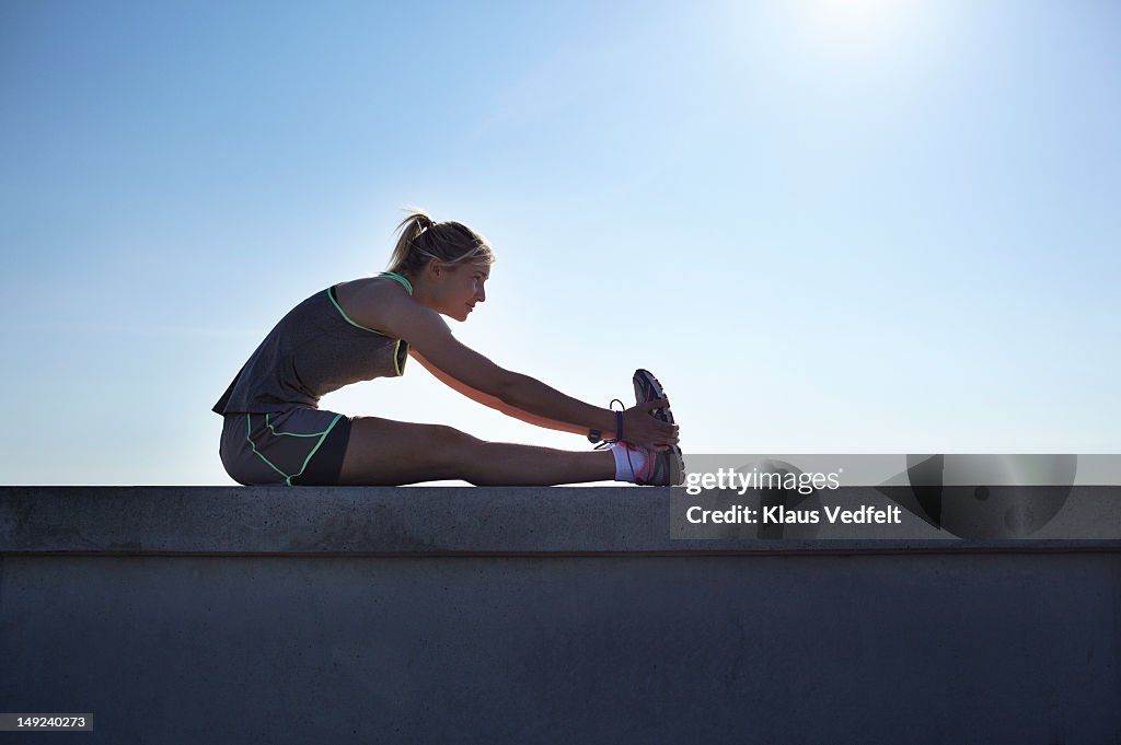 Female runner stretching at urban setting