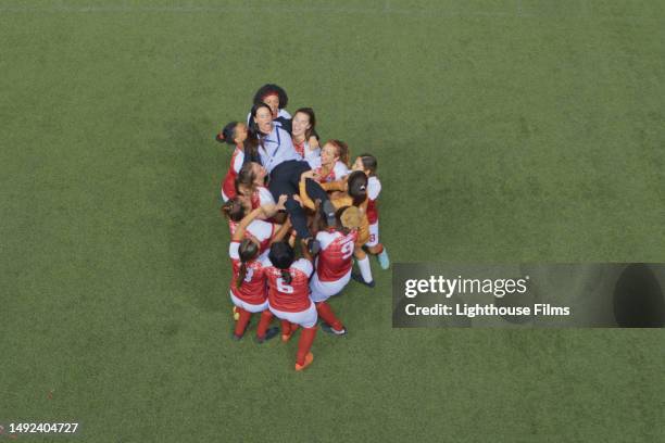 women soccer players lift their coach up to the air in celebration - airboard stock pictures, royalty-free photos & images