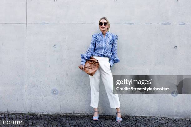 Influencer Tamara von Nayhauss, wearing white pants by Zara, a blue colores blouse with quillings by Maison Common, blue sandals by Miu Miu, a brown...
