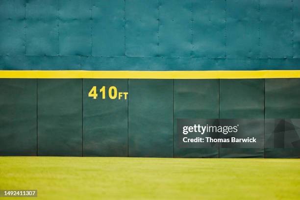 wide shot of outfield wall and grass in baseball stadium - baseball outfield wall stock pictures, royalty-free photos & images