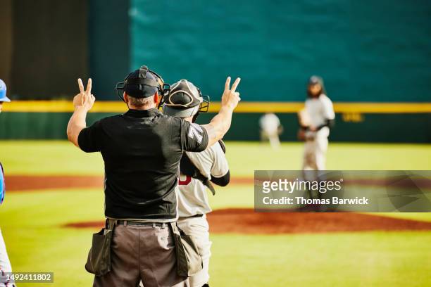 medium wide shot umpire showing balls and strikes during baseball game - referee uniform stock pictures, royalty-free photos & images