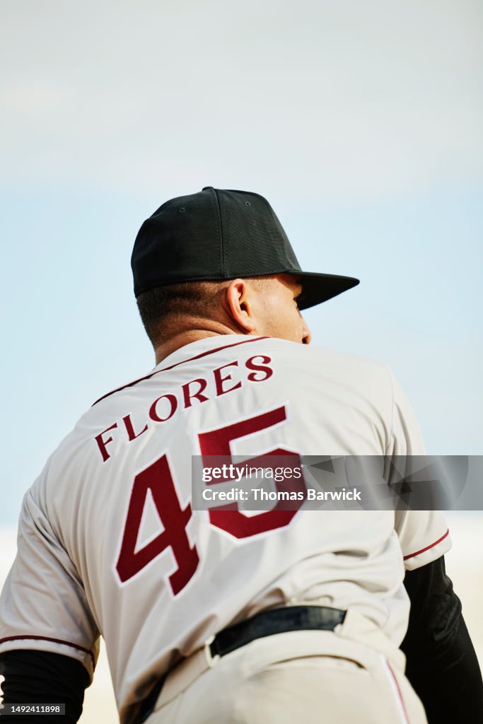 Medium shot rear view baseball player throwing ball while during game