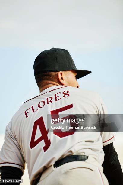 medium shot rear view baseball player throwing ball while during game - divisa da baseball foto e immagini stock