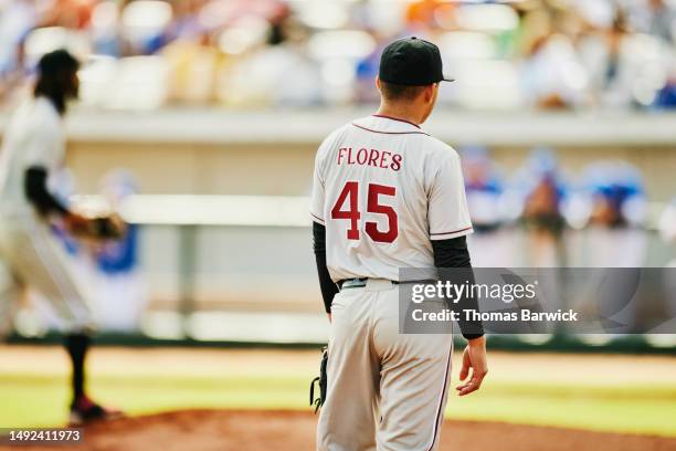 medium wide shot rear view infielder during professional baseball game - baseball uniform stock pictures, royalty-free photos & images