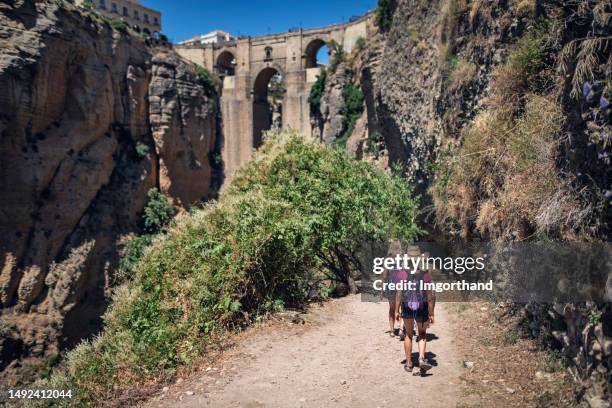 happy family hiking towards the magnificent puente nuevo in ronda, andalusia, spain. - andalusia stock pictures, royalty-free photos & images