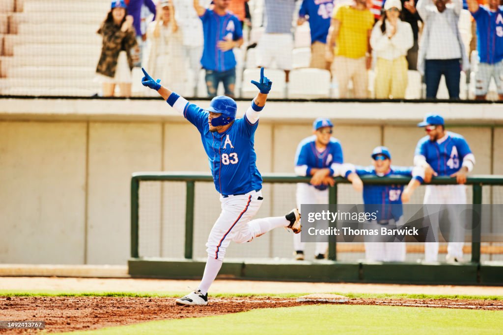 Wide shot baseball player celebrating home run while running bases