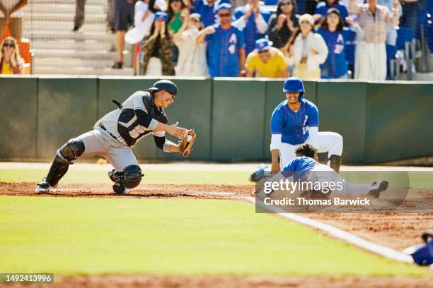 wide shot catcher diving for tag on sliding runner during baseball game - linebacker stock pictures, royalty-free photos & images