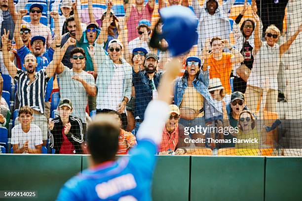 medium shot baseball player saluting cheering crowd after hitting home run - baseball fans stock pictures, royalty-free photos & images