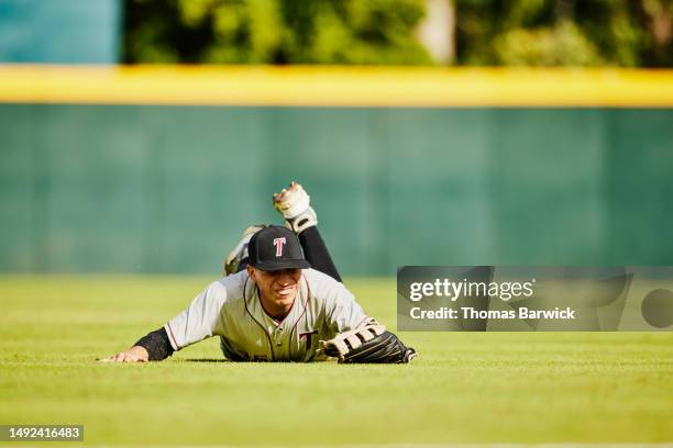 wide shot outfielder sliding on grass after catch during baseball game - catchers mitt stock pictures, royalty-free photos & images