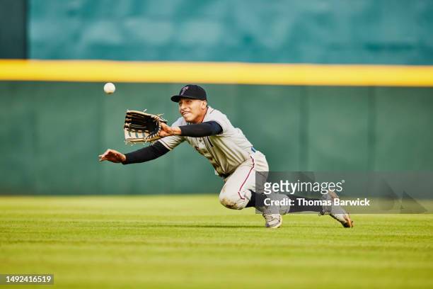 wide shot of outfielder diving for catch during baseball game - catchers mitt stock pictures, royalty-free photos & images