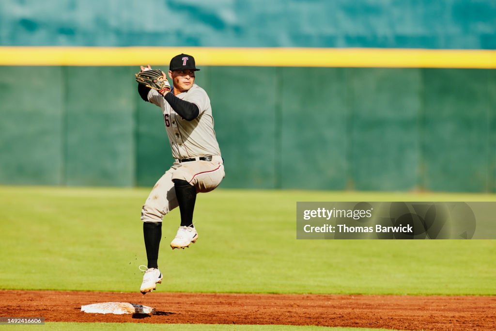 Wide shot second baseball throwing to first base during baseball game