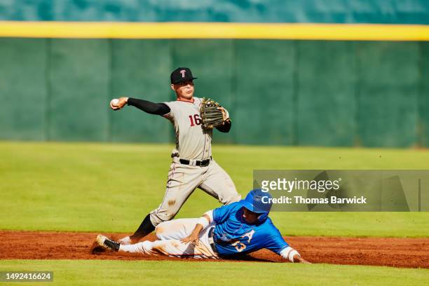 wide shot second baseman throwing to first base during baseball game - baseball base stock-fotos und bilder
