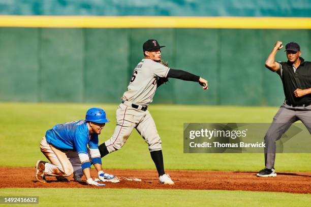 wide shot second baseman throwing to first base during baseball game - referee shirt stock pictures, royalty-free photos & images