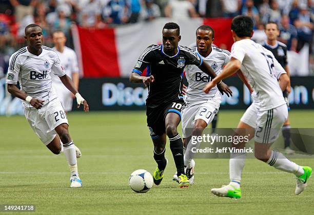 Gershon Koffie, Dane Richards and Young-Pyo Lee of the Vancouver Whitecaps FC look on as Simon Dawkins of the San Jose Earthquakes dribbles the ball...