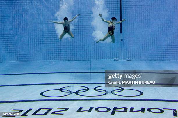 Divers are pictured in the pool after performing their jump during a training session, on July 25, 2012 at the Aquatics center in London, two days...