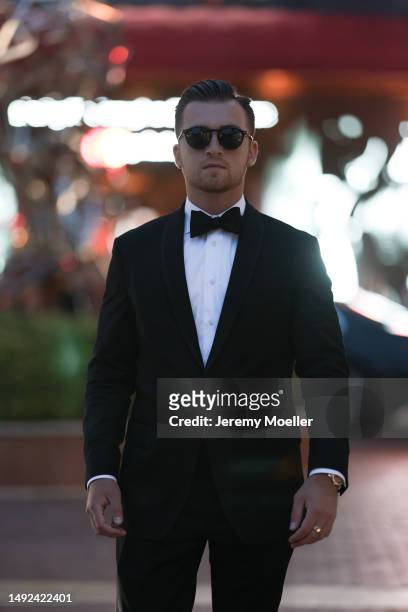 Austin Zelan seen wearing a black and white suit, black pants, black bow tie and black leather shoes and sunglasses during the 76th Cannes film...