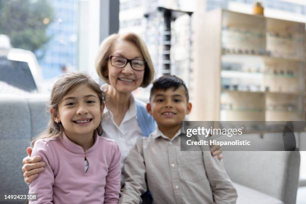 happy grandmother smiling with her grandchildren at the optometry store - legal guardian stock pictures, royalty-free photos & images