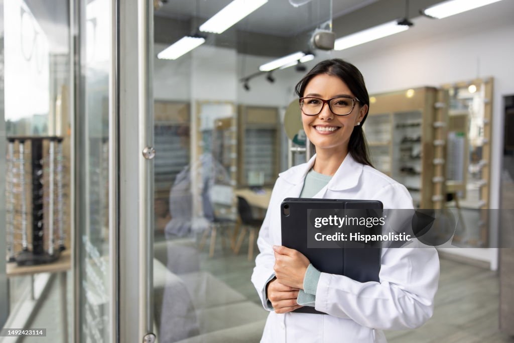 Happy optician working at an optometry store using a tablet