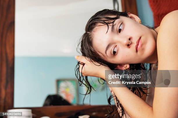 young woman taking care of her hair at home - cabello mojado fotografías e imágenes de stock