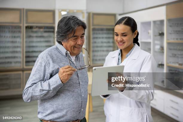 optician holding an eye chart for a senior patient to read the letters - ophthalmologist chart stock pictures, royalty-free photos & images