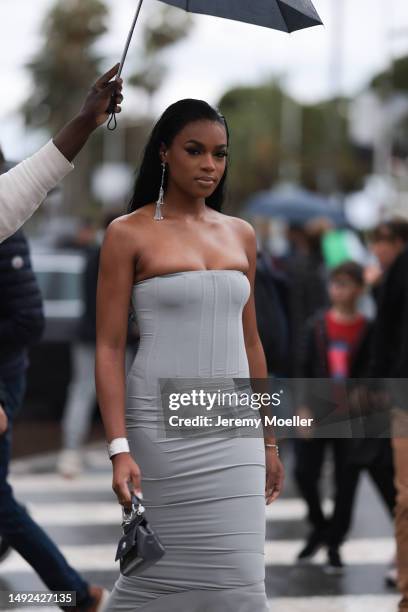 Didi Stone is seen wearing a grey tight and off-shoulder dress, black mini handbag and silver long shimmery earrings during the 76th Cannes film...