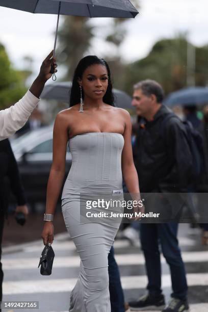 Didi Stone is seen wearing a grey tight and off-shoulder dress, black mini handbag and silver long shimmery earrings during the 76th Cannes film...