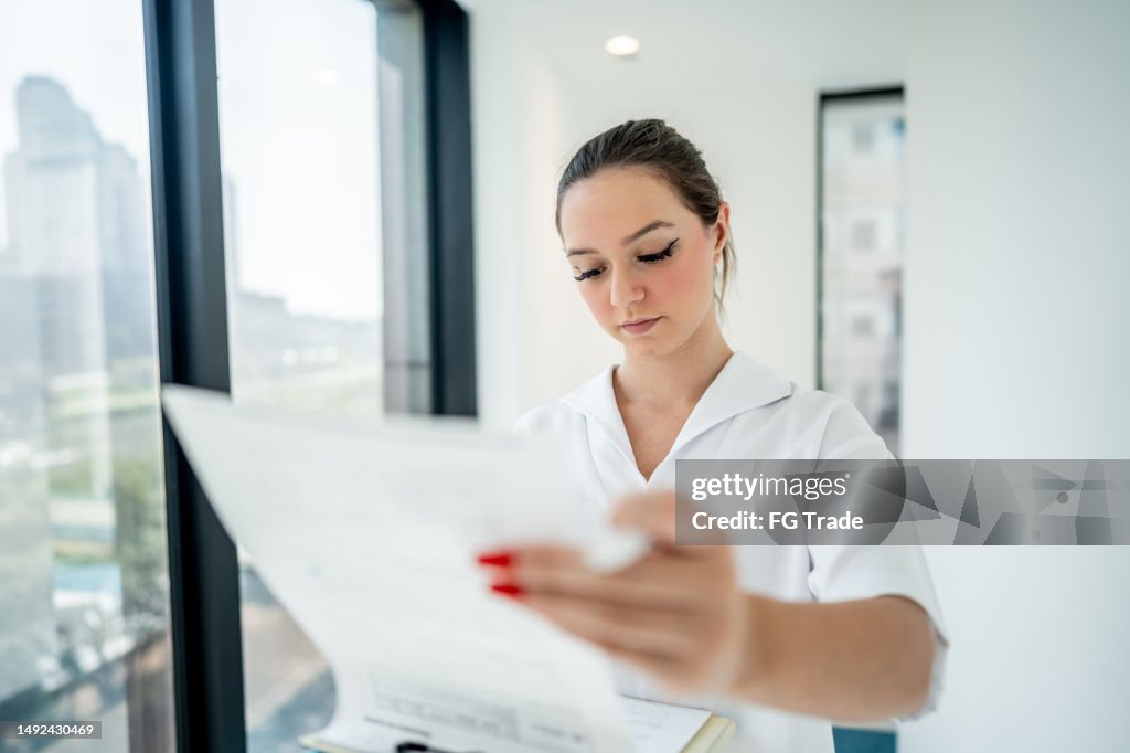 Nurse walking while reading patient's medical record in the hospital