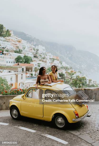two woman in a small, open topped, vintage yellow car. - indian tour guide stock pictures, royalty-free photos & images