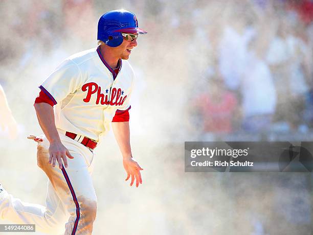 Mike Fontenot of the Philadelphia Phillies reacts in a cloud of dust after scoring the game winning run on a single by teammate Jimmy Rollins in the...