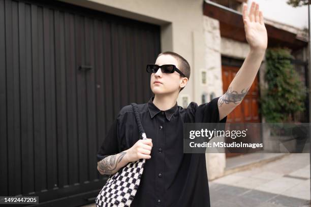 portrait of a transgender male looking at the camera. he is wearing black cool outfit - woman short hair serious stock pictures, royalty-free photos & images