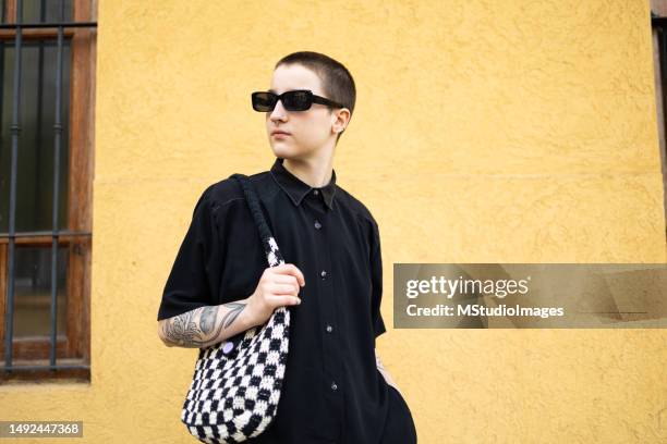 retrato de un hombre transgénero vestido con un traje negro genial. fondo amarillo - ftm fotografías e imágenes de stock