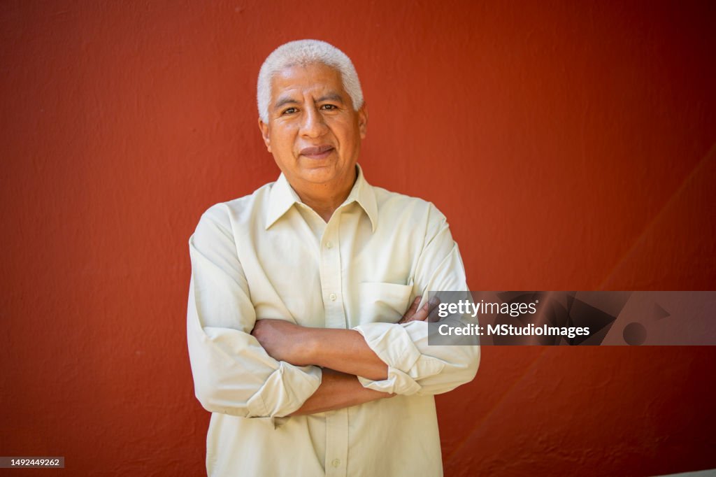 Portrait of a Latin senior man looking at the camera on a red background