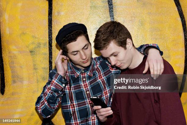 two boys against grafitti wall with mobile phone - portraits fun mobile wall stock-fotos und bilder