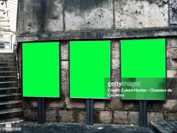 three billboards with green background in front of a patinated stone wall and cobbled street with stairs in lausanne, switzerland - triple stock-fotos und bilder