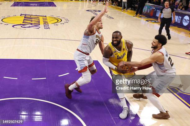 LeBron James of the Los Angeles Lakers is defended on the final play of the game by Aaron Gordon and Jamal Murray of the Denver Nuggets in game four...