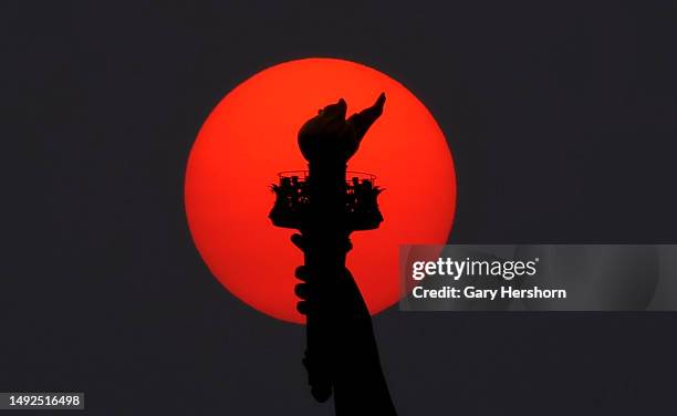 The sun is shrouded as it sets behind the Statue of Liberty in a hazy sky caused by smoke drifting into the Northeast of the U.S. From wildfires in...