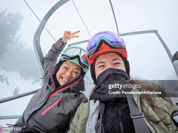 asian senior mother, multiracial daughter taking selfie on ski lift - woman on ski lift stock pictures, royalty-free photos & images