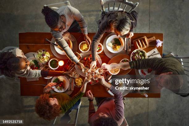 oben blick auf glückliche freunde, die während des mittagessens am esstisch anstoßen. - friends toasting above table stock-fotos und bilder