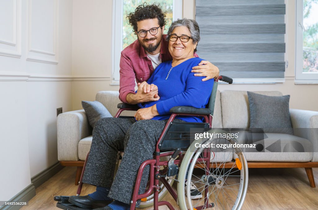 Mid adult man hugging his disabled mother at home